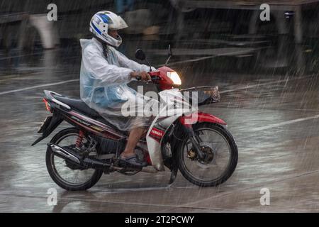 SAMUT PRAKAN, THAILAND, OKT 03 2023, der Mototaxi-Fahrer in einer Regenmantelfahrt auf der Straße bei starkem Regen Stockfoto