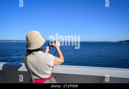 Frau, die Fotos mit dem Smartphone auf der Fähre in Elliott Bay macht. Seattle. Bundesstaat Washington. Stockfoto