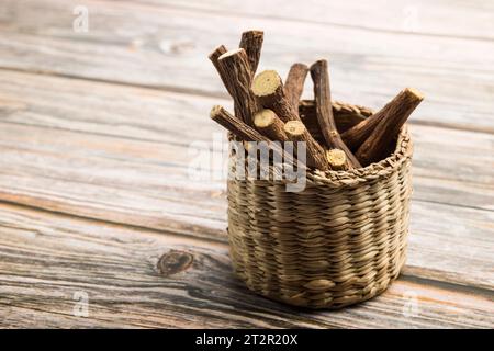 Stäbchen mit Lakritzwurzeln auf einem kleinen Korb auf Holztisch. Stockfoto
