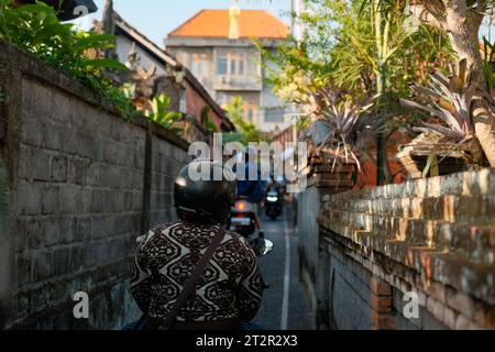 Genießen Sie den lebhaften Geist von Ubud, Bali, während die Menschen charmante Seitenstraßen auf Motorrädern erkunden. Lebhafte Farben, lebhafte Energie und ein Gefühl von Adven Stockfoto