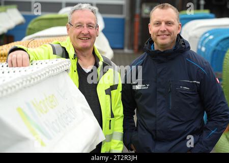Norden, Deutschland. Oktober 2023. Vollmar Constapel, Leiter Bäder der Wirtschaftsbetriebe Norden (l), und Standleiter Harald Lübbers (r) stehen vor der Auktion an den Liegen. Nordseeliebhaber und Schnäppchenjäger haben am Samstag gegen Saisonende im Ostfriesischen Norddeich versteigert. Insgesamt standen rund 50 der massiven Strandmöbel zum Verkauf. Quelle: Lars Penning/dpa/Alamy Live News Stockfoto
