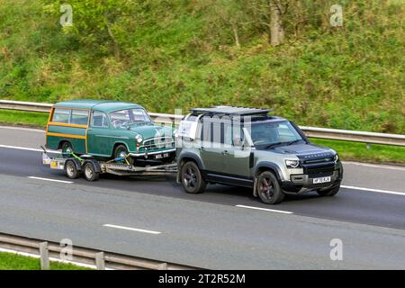 2020 Land Rover Defender X MHEV Auto I6 P400 AWD MHEV Auto Start/Stopp Green LCV Hardtop Van Benzin 2996 ccm klassischer 1955 Green Morris Oxford 1489 ccm Kombi auf PKW-Anhänger; Fahrt mit Geschwindigkeit auf der Autobahn M6 im Großraum Manchester, Großbritannien Stockfoto