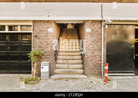 Ein Backsteingebäude mit zwei Garagen auf der Vorderseite und Treppen, die in die zweite Etage in einer Gasse führen Stockfoto