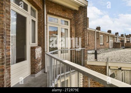 Ein Balkon mit Ziegelwänden und weißen Zierleisten um das Geländer, an einem sonnigen Tag im Frühling - Stockfoto Stockfoto