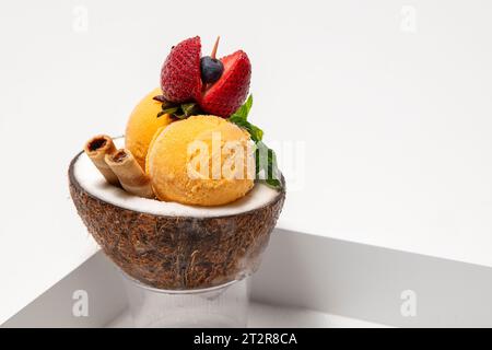 Köstliches cremiges Eis im neutralen Hintergrund der Kokosnussschale. Stockfoto