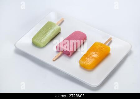 Set glasierter Eisriegel auf einem Stock; verschiedene Farben, isoliert auf weißem Hintergrund Stockfoto
