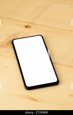Foto des Smartphones auf einem Holztisch, während der weiße Bildschirm gezeigt wird. Stockfoto