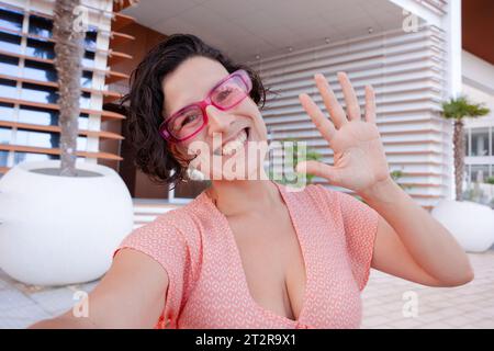 Vorderansicht eines lächelnden jungen Latinos, der der Kamera zuwinkt Stockfoto