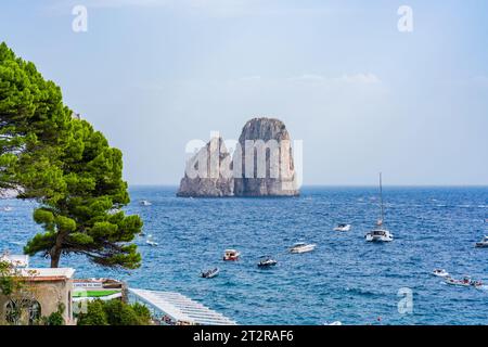 CAPRI, ITALIEN - 22. SEPTEMBER 2023: Ausflugsboote bringen Touristen zu den Faraglioni Rocks. Die Insel Capri ist berühmt für ihre zerklüftete Landschaft. Im Sommer seine Dramati Stockfoto