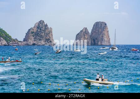 CAPRI, ITALIEN - 22. SEPTEMBER 2023: Ausflugsboote bringen Touristen zu den Faraglioni Rocks. Die Insel Capri ist berühmt für ihre zerklüftete Landschaft. Im Sommer seine Dramati Stockfoto