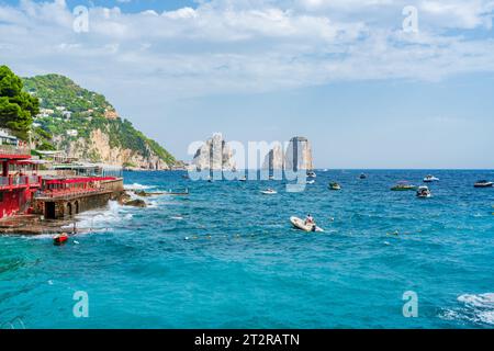 CAPRI, ITALIEN - 22. SEPTEMBER 2023: Ausflugsboote bringen Touristen zu den Faraglioni Rocks. Die Insel Capri ist berühmt für ihre zerklüftete Landschaft. Im Sommer seine Dramati Stockfoto