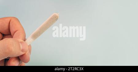 Vorbereitung von CannabisJoint mit Tabak und Papierrollen mit Marihuana-Knospen auf blauem Hintergrund. Die Andeutung des Marihuana-Missbrauchs. Cannabis Legalizati Stockfoto
