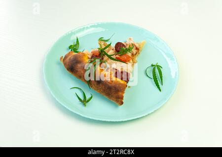 Hausgemachte Pizza mit Marihuana-Cannabisblättern auf weißem Hintergrund. Frisches medizinisches Marihuana, Cannabis dekoriert auf Pizza. Stockfoto