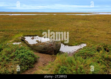 Ein verrottetes Holzboot, das in den Salzwiesen von Blakeney, Norfolk, England, Großbritannien verrottet Stockfoto