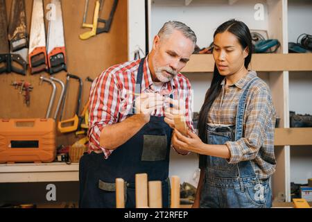 Handwerker, Senior-Mann, der weibliche Lehrlinge in der Holzwerkstatt unterrichtet Stockfoto