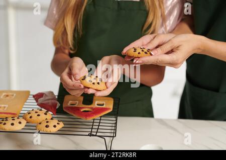 Hände von Mutter und Tochter, die Schokoladenchips auf Kühlregal legen Stockfoto