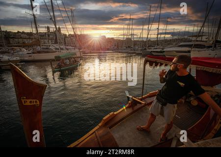 Die maltesische Dghajsa (ähnlich einer Gondel) transportiert Passagiere zwischen Valletta und Birgu in Malta, während die Sonne untergeht Stockfoto