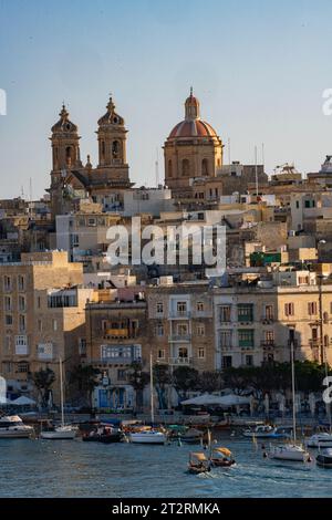 Die maltesische Dghajsa (ähnlich einer Gondel) transportiert Passagiere von Valletta nach Senglea mit der Kirche St. Lawrence in der Ferne, Malta Stockfoto