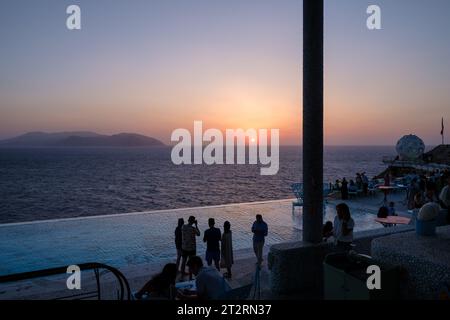 IOS, Griechenland - 11. September 2023 : Junge Menschen treffen sich an einem Pool in einer Lounge Bar, um den Sonnenuntergang in iOS kykladen Griechenland zu beobachten Stockfoto