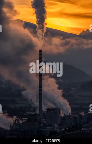 Fabrik mit Kamin und Rauch und Dampf mit bunten Sonnenuntergang im Hintergrund Stockfoto