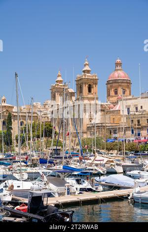 Vittoriosa, Malta - 17. Juni 2023: Stiftskirche St. Lorenz, durch Masten von Booten gesehen Segeln, Vittoriosa Stockfoto