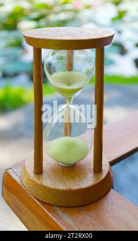 Sanduhr auf Gartentisch mit Seerosenteich im Hintergrund Stockfoto