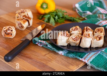 Shawarma-Stücke auf Holztisch mit süßen Paprika im Hintergrund und Messer Stockfoto