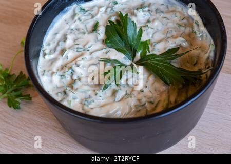 Petersilie mit Tahini gemischt und serviert auf schwarzem Teller mit hölzernem Hintergrund Stockfoto