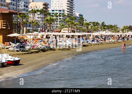 Touristen Sonnenbaden und Schwimmen am Strand von Finikoudes, Larnaca, Zypern Stockfoto