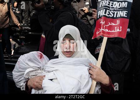 London, UK, 21. Oktober 2023. Eine Frau wiegt ein gefälschtes totes Baby während eines Protestes, der von Marble Arch zur Downing Street vorgeht und die palästinensische Sache im Konflikt zwischen Hamas und Israel unterstützt. (Tennessee Jones - Alamy Live News) Stockfoto