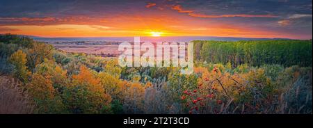 Herbstabend über dem Tal. Wunderschönes Herbstpanorama mit buntem Wald und orangefarbenem Sonnenuntergang im oktober Stockfoto