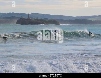 Surfer mit Mouro Island am Eingang zur Bucht mit starken Wellen an einem sonnigen Herbstmorgen Sardinero Santander Cantabria Spanien Stockfoto