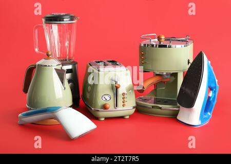 Satz moderner Haushaltsgeräte auf rotem Hintergrund Stockfoto