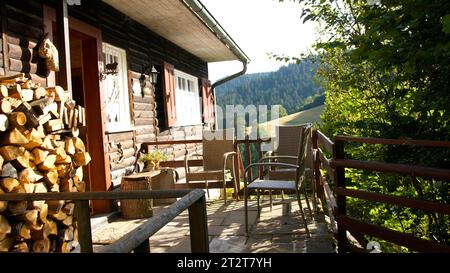 Eine atemberaubende rustikale alte Hütte mit einer Reihe von Gartenmöbeln, einschließlich einem Tisch und Stühlen Stockfoto