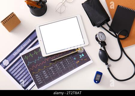 Tablet-Computer mit medizinischem Zubehör auf weißem Schreibtisch, Draufsicht Stockfoto