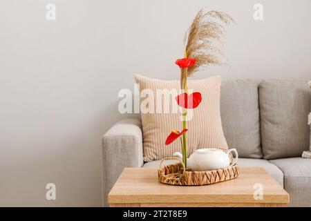 Wunderschönes Ikebana mit Teekanne auf dem Tisch im Wohnzimmer Stockfoto