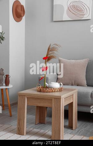 Wunderschönes Ikebana mit Teekanne auf dem Tisch im Wohnzimmer Stockfoto