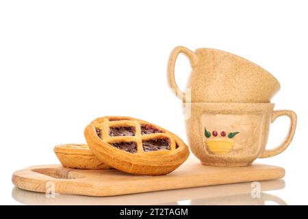 Zwei Shortbread-Kekse mit Marmelade auf einem hölzernen Küchenbrett mit zwei Keramikbechern Stockfoto