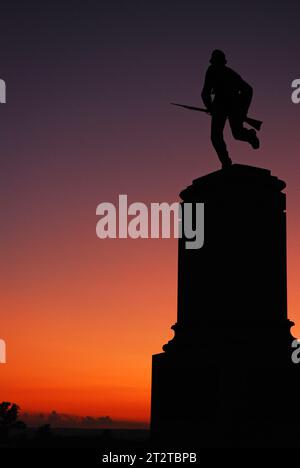 Ein Denkmal für die erste Minnesota Volunteer Infanterie zeigt einen Soldaten mit einem Bajoneten und Silhouetten vor einem Abendhimmel in Gettysburg Stockfoto