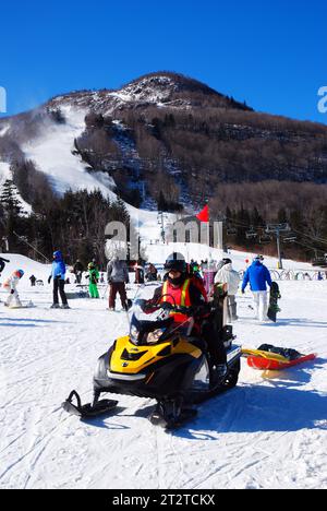 Ein Rettungsteam auf einem Schneemobil bringt eine Bahre in eine Notsituation für einen Skifahrer auf den Berghängen Stockfoto