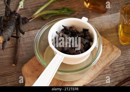 Hausgemachte Beinwell- oder Strickwurzelsalbe durch ein weißes Sieb absaugen Stockfoto