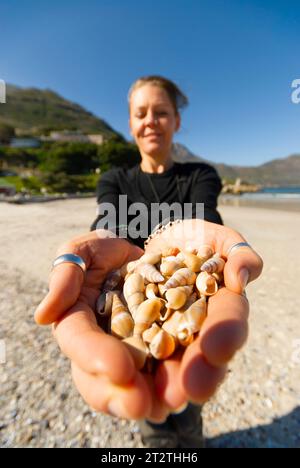 Eine Frau hält eine Handvoll Muscheln am Strand in Kapstadt Stockfoto