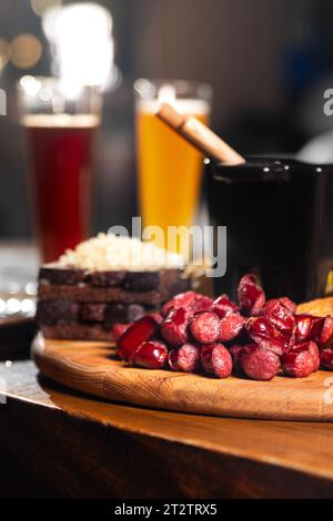 Biervorspeise mit gesalzenen Erdnüssen, Würstchen und Croutons mit Knoblauch auf einem Teller auf einem Holztisch. Vertikale Orientierung, Nahaufnahme, keine Leute, Polizist Stockfoto
