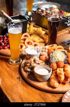 Biervorspeise mit gesalzenen Erdnüssen, Würstchen und Croutons mit Knoblauch auf einem Teller auf einem Holztisch. Vertikale Orientierung, Nahaufnahme, keine Leute, Polizist Stockfoto