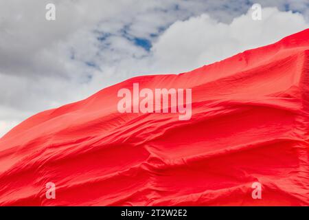 Rote Textilfahne im Wind gegen den blauen Himmel, Designelement Stockfoto