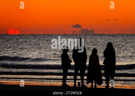 Isle Of Palms, Usa. Oktober 2023. Eine Familie, die vom Sonnenaufgang umgeben ist, während sie am 21. Oktober 2023 in Isle of Palms, South Carolina, am Horizont des Atlantischen Ozeans beobachten, wie die Sonne über dem Horizont des Atlantiks kommt. Quelle: Richard Ellis/Richard Ellis/Alamy Live News Stockfoto
