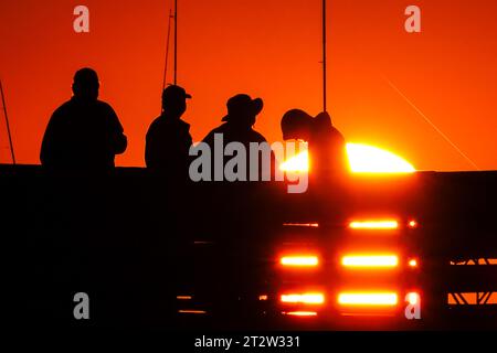 Isle Of Palms, Usa. Oktober 2023. Am Isle of Palms Pier am 19. Oktober 2023 in Isle of Palms, South Carolina, wartet eine Gruppe von Fischern, die bei Sonnenaufgang in Silhouetten auf den großen Fisch. Quelle: Richard Ellis/Richard Ellis/Alamy Live News Stockfoto