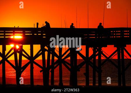 Isle Of Palms, Usa. Oktober 2023. Am Isle of Palms Pier am 19. Oktober 2023 in Isle of Palms, South Carolina, wartet eine Gruppe von Fischern, die bei Sonnenaufgang in Silhouetten auf den großen Fisch. Quelle: Richard Ellis/Richard Ellis/Alamy Live News Stockfoto