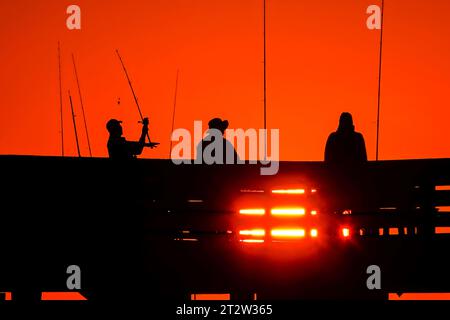 Isle Of Palms, Usa. Oktober 2023. Am Isle of Palms Pier am 19. Oktober 2023 in Isle of Palms, South Carolina, wartet eine Gruppe von Fischern, die bei Sonnenaufgang in Silhouetten auf den großen Fisch. Quelle: Richard Ellis/Richard Ellis/Alamy Live News Stockfoto