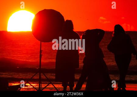 Isle Of Palms, Usa. Oktober 2023. Am 21. Oktober 2023 in Isle of Palms, South Carolina, hält ein Fotograf eine Fotosession ab, die vom Sonnenaufgang über den Horizont des Atlantiks geschildert wird. Quelle: Richard Ellis/Richard Ellis/Alamy Live News Stockfoto